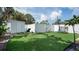 Spacious backyard with artificial turf, a storage shed, and a white fence for privacy at 500 62Nd S St, St Petersburg, FL 33707