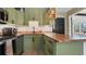 Functional kitchen showcasing green cabinetry, butcher block countertops, and stainless steel appliances at 500 62Nd S St, St Petersburg, FL 33707