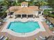Aerial of a beautiful community pool with shade pavilion surrounded by lush greenery, palm trees, and nearby condos at 7903 Seminole Blvd # 2203, Seminole, FL 33772