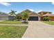 This home is in a suburban neighborhood, featuring a well-manicured lawn and tropical landscaping at 8620 Sandy Plains Dr, Riverview, FL 33578
