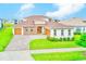 Aerial view of a well-manicured home with a three car garage, brick accents, and green lawn at 8717 Sanders Tree Loop, Wesley Chapel, FL 33545