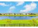 Beautiful backyard view featuring a pond surrounded by green lawns and neighboring houses under a blue sky at 8717 Sanders Tree Loop, Wesley Chapel, FL 33545