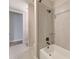 Neutral bathroom featuring a shower-tub combo with gray tile surround and glass partition at 8717 Sanders Tree Loop, Wesley Chapel, FL 33545