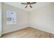 Bright bedroom with light wood floors, a ceiling fan, and a window overlooking a green yard at 8717 Sanders Tree Loop, Wesley Chapel, FL 33545