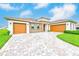 A paver driveway leading to a three-car garage and beautiful landscaping at 8717 Sanders Tree Loop, Wesley Chapel, FL 33545