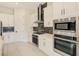 Modern kitchen featuring stainless steel appliances, white cabinets, and sleek black backsplash at 8717 Sanders Tree Loop, Wesley Chapel, FL 33545