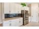 Bright kitchen with stainless steel refrigerator, white cabinets, and dark backsplash at 8717 Sanders Tree Loop, Wesley Chapel, FL 33545