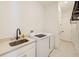 Laundry room with sink, modern washer and dryer, and plenty of storage space at 8717 Sanders Tree Loop, Wesley Chapel, FL 33545