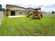 Spacious backyard featuring a green lawn, patio, and wooden playground at 9650 Sage Creek Dr, Ruskin, FL 33573