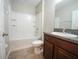 Bathroom features a toilet, sink with dark cabinets, and a tub with white tiling at 9650 Sage Creek Dr, Ruskin, FL 33573