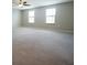Expansive bonus room featuring two windows, carpeted flooring, and a ceiling fan at 9650 Sage Creek Dr, Ruskin, FL 33573