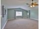 Spacious bonus room featuring a vaulted ceiling, large window, and neutral carpeting at 12305 Freesia Ct, Riverview, FL 33569