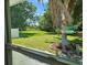 Backyard view through window featuring green grass and shade trees extending to the waterfront at 2152 Mckinley St, Clearwater, FL 33765