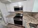 Modern kitchen featuring stainless steel appliances, granite countertops, and white cabinetry at 2152 Mckinley St, Clearwater, FL 33765