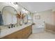 Bright bathroom featuring a double vanity with marble countertop, soaking tub, and neutral tile flooring at 2226 Charleston Park Dr, North Port, FL 34287