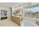 Bright bathroom showcasing double vanity with marble countertop, soaking tub, and view from large window at 2226 Charleston Park Dr, North Port, FL 34287