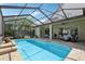 The screened in pool area includes a covered patio with furniture and lush landscaping at 23346 Abercorn Ln, Land O Lakes, FL 34639