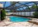 Inviting screened-in pool with stone accents and surrounding greenery at 2421 Eagle Chase Dr, Palm Harbor, FL 34683