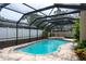 Inviting screened-in pool with stone accents and surrounding greenery at 2421 Eagle Chase Dr, Palm Harbor, FL 34683