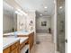 Well-lit bathroom featuring double sinks, vanity, soaking tub, and walk-in shower at 3805 Gulf Blvd # 401, St Pete Beach, FL 33706
