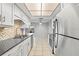 Galley kitchen featuring stainless appliances, dark countertops, tile backsplash, and white cabinets at 7108 14Th Nw Ave, Bradenton, FL 34209