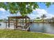 Waterfront home with a dock featuring seating and a canopy, perfect for enjoying the serene water views at 911 Sago Palm Way Way, Apollo Beach, FL 33572