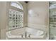 Close up of a soaking tub with tile surround and a glass block window that brings in natural light at 15209 Hammock Chase Ct, Odessa, FL 33556
