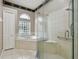 Bright bathroom featuring a separate shower with glass door and soaking tub with tile surround and glass block window at 15209 Hammock Chase Ct, Odessa, FL 33556