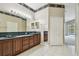 Bathroom featuring a double sink vanity with wood cabinets, a large mirror, and access to a walk-in closet at 15209 Hammock Chase Ct, Odessa, FL 33556