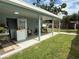 A covered patio offers an outdoor workspace with a laundry area, overlooking the spacious backyard and a bird coop at 2927 W Henry Ave, Tampa, FL 33614