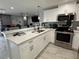 Bright kitchen with white cabinets, stainless steel appliances, and an open view into the living room at 2927 W Henry Ave, Tampa, FL 33614