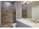 Modern bathroom featuring a granite countertop, gray vanity, large mirror and slate-style tile shower with niche at 3298 Covered Bridge W Dr, Dunedin, FL 34698