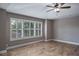 Bedroom featuring tray ceiling, ceiling fan, plantation shutters and wood-look tile flooring at 3298 Covered Bridge W Dr, Dunedin, FL 34698