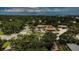 Aerial view of neighborhood with a commercial business nearby with parking, lush trees and a glimpse of the ocean at 878 Franklin Cir, Palm Harbor, FL 34683
