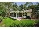 A charming backyard features a screened-in porch, lush green grass, mature trees, and a privacy fence at 878 Franklin Cir, Palm Harbor, FL 34683