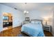 Bedroom with a view into ensuite bathroom, featuring a queen bed, wood floors, and a side table at 878 Franklin Cir, Palm Harbor, FL 34683