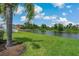 A scenic view of the backyard, showcasing lush lawn and a peaceful lake beyond a picket fence at 20115 Nob Oak Ave, Tampa, FL 33647