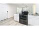 Sleek kitchen features black range and white cabinets with granite countertops at 2101 E Ellicott St, Tampa, FL 33610