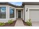 Inviting entryway with a dark front door, decorative plants, and a brick paver path to the entrance at 2743 Winding Creek Trl, North Port, FL 34289