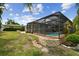 Spacious backyard featuring a screened-in pool area, stone retaining walls, and lush green landscaping at 3921 E Eden Roc Cir, Tampa, FL 33634