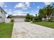 Inviting single-story home featuring a two-car garage, mature palm trees, and a cracked concrete driveway at 3921 E Eden Roc Cir, Tampa, FL 33634