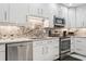 Modern kitchen with white cabinets, stainless steel appliances, and stunning marble backsplash at 4104 Northmeadow Cir # 4104, Tampa, FL 33618