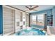 A cozy blue bedroom with a ceiling fan, a window with a view, and a large built-in bookshelf at 4900 Brittany S Dr # 1011, St Petersburg, FL 33715