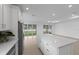 Open-concept kitchen featuring a large island, stainless steel appliances, and sliding doors to the backyard at 6982 Minneola Ct, Nokomis, FL 34275