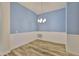 Dining area with wood-look floors, blue accent wall, and modern chandelier at 12218 Avondale Oak Pl, Riverview, FL 33578
