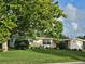 Charming single-story home with lush front lawn, mature landscaping, and a welcoming red front door at 1596 S Evergreen Ave, Clearwater, FL 33756