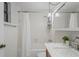 The white tiled full bathroom is features a shower and tub combo, and a sink at 1980 Tahitian Pl # 10, Dunedin, FL 34698
