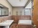 A tiled bathroom featuring a large tub, a decorative mirror, and a tiled sink at 5110 Lake Valencia E Blvd, Palm Harbor, FL 34684