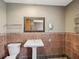 A tiled bathroom with a pedestal sink, a large mirror, and a toilet at 5110 Lake Valencia E Blvd, Palm Harbor, FL 34684