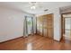 Bedroom featuring hardwood floors, a window with curtains, and a closet with shuttered doors at 5110 Lake Valencia E Blvd, Palm Harbor, FL 34684